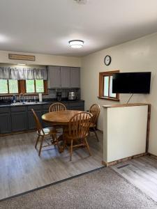 a kitchen with a table and chairs and a tv at Maple Ridge Trail Side Cabin in Crandon
