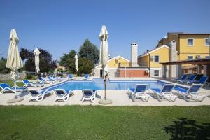 a swimming pool with lounge chairs and umbrellas at Villa Suzanne in Banjole