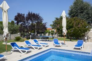a group of chairs and umbrellas next to a pool at Villa Suzanne in Banjole