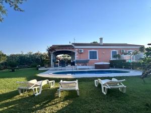 a yard with chairs and a house and a pool at Villa Funtana Cortese in Orosei