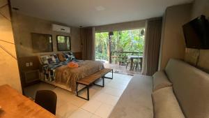 a bedroom with a bed and a couch and a tv at Villas Pratagy Flor de Lis 901-Studio in Maceió