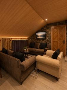 a living room with two couches and a tv at The Cozy Cottage, Dunga Gali in Dunga Gali