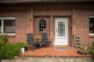 a brick house with two chairs and a white door at Narnia in Heede