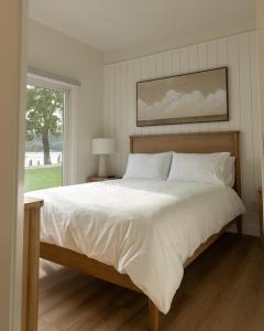 a bedroom with a large white bed with a window at The Point on Wood Lake in Lake Country