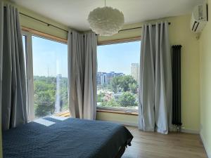 a bedroom with a bed and a large window at Altura House in Almaty