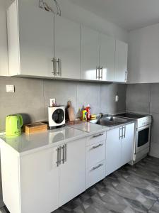 a white kitchen with white cabinets and a sink at Vikendica Fenix in Banja Luka