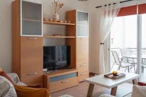 a living room with a entertainment center with a flat screen tv at Chloraka Sea View Apt with Pool in Khlorakas