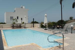 a swimming pool with tables and chairs and a building at Chloraka Sea View Apt with Pool in Khlorakas