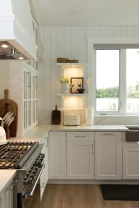 a kitchen with white cabinets and a stove top oven at The Point on Wood Lake in Lake Country +21 photos