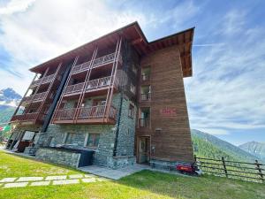 a building on a hill with mountains in the background at Maison Fosson in Champoluc