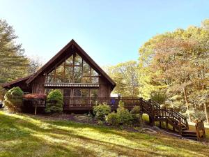 a large wooden house with benches in the grass at The Luxury Cabin at Deep Hollow in Narrowsburg