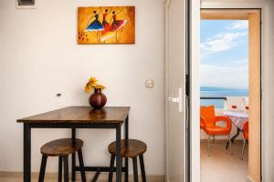 a dining room table with stools and a painting on the wall at Apartman Štorija with Private Jacuzzi-Brela in Brela