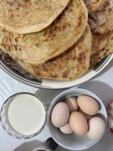 a plate of pancakes with eggs and a bowl of milk at Ak-Bulak in Kurmenty +21 photos