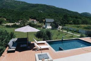 a swimming pool with an umbrella and a chair at Villa Harmonia in Glavati
