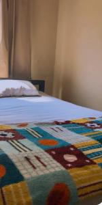 a bed with a colorful blanket on top of it at hotel larena in Sete Lagoas