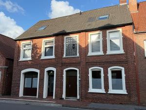 ein rotes Backsteingebäude mit weißen Fenstern und Türen in der Unterkunft Brigg in Emden