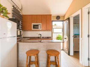 a kitchen with wooden cabinets and two stools at Sunny Haven I in Maspalomas