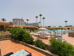 a resort with a swimming pool and chairs and a resort at Sunny Haven I in Maspalomas