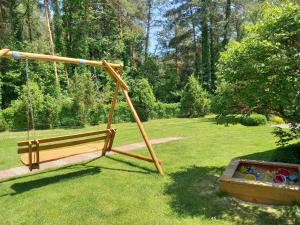 a wooden swing in a park with a yard at Pod lasem domek letniskowy in Susiec +10 photos