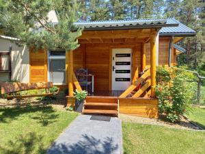 a wooden cabin with a porch and a door at Pod lasem domek letniskowy in Susiec