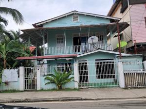 a blue house with a white fence in front of it at Hostal South beach in Carenero