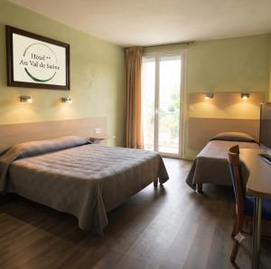 a hotel room with two beds and a window at Hôtel Au Val De Saône PARKING GRATUIT in Sathonay-Camp