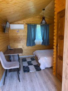 a bedroom with a bed and a desk in a log cabin at Casa Fericirii in Cârțișoara