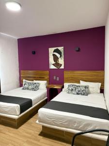 two beds in a room with a purple wall at Hotel Jar8 Bule Frente al Mar in Boca del Río +60 photos