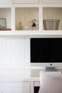 a computer monitor sitting on top of a white desk at Playa Penthouse (Ocean Views) in Carpinteria +1 photo
