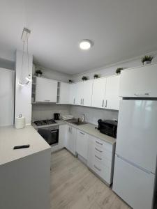 a kitchen with white cabinets and a white refrigerator at Apartment in Ploiești 3 in Ploieşti +9 photos