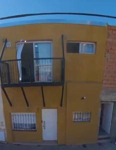 a yellow building with a balcony and two doors at CENTENO CASI 9 DE JULIO in Santa Rosa