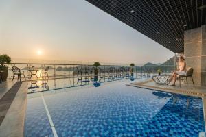 a woman sitting in a chair next to a swimming pool at Cat Ba Paradise Hotel - Sirocco Sky Bar & Massage in Cat Ba