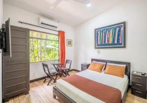 a bedroom with a bed and a table and a window at Hotel Jaco Lodge in Jacó