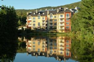 a large apartment complex reflected in a lake at Tremblant Prestige - BONDURANT 95-10 in Mont-Tremblant
