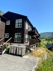 a large black house with a large deck and a building at Røldal Overnatting in Røldal