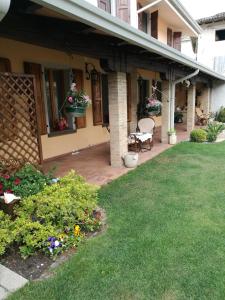ein Haus mit Terrasse und einem Garten mit Blumen in der Unterkunft Alberta in Bertiolo + 17 Fotos