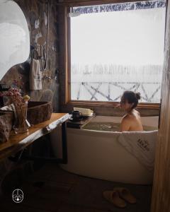 a woman sitting in a bath tub in a window at Ecohotel Mauka in Pasto