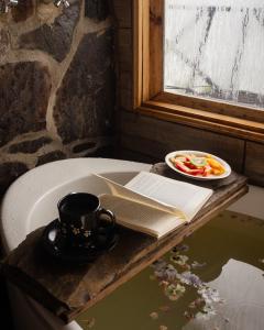 a cup of coffee and a book on a table with a plate of food at Ecohotel Mauka in Pasto