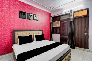 a bedroom with a bed with a red wall at Hotel O A-1 Guest House in New Delhi