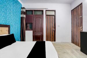 a bedroom with a bed and a wooden door at Hotel O A-1 Guest House in New Delhi