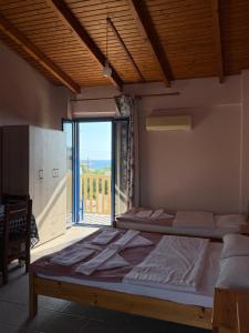 two beds in a room with a large window at Ilios Kalamaki in Kalamaki