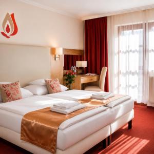 a hotel room with two beds and a desk at Hotel Piroska in Bük