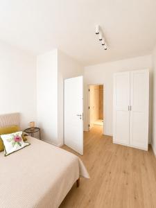 a white bedroom with a bed and a wooden floor at Casa Granata in Caserta