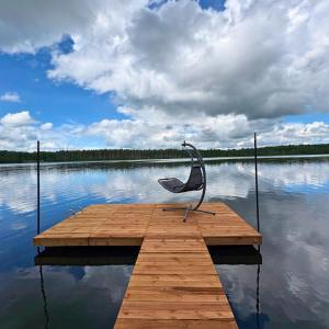 a metal chair sitting on a dock on a lake at Rātes Krasti - Rasa - holiday house with sauna and lakeview in Lejasciems