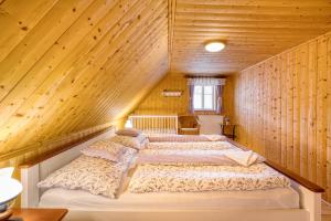 two beds in a room with wooden walls at Chata Vanilka in Bělá pod Pradědem