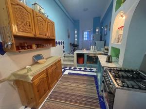 a kitchen with blue walls and wooden cabinets at EL Fouly Villa beach front -North Coast فيلا لمة العيله الفولي - سيدي كرير - الساحل الشمالي in Abû Zeira