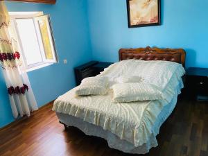 a bedroom with a bed with blue walls and a window at Gariks house in Lichkʼ