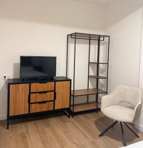 ein Wohnzimmer mit Fernseher und Sessel in der Unterkunft O Abeiro in Corcubión