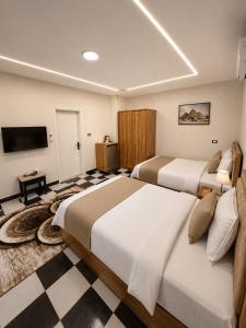 a hotel room with two beds and a flat screen tv at GREAT PYRAMIDS View lodge in Cairo +57 photos