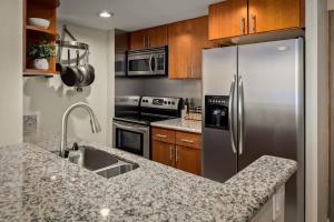a kitchen with a stainless steel refrigerator and wooden cabinets at Urban Gallery Loft - King Bed - Larimer Square in Denver